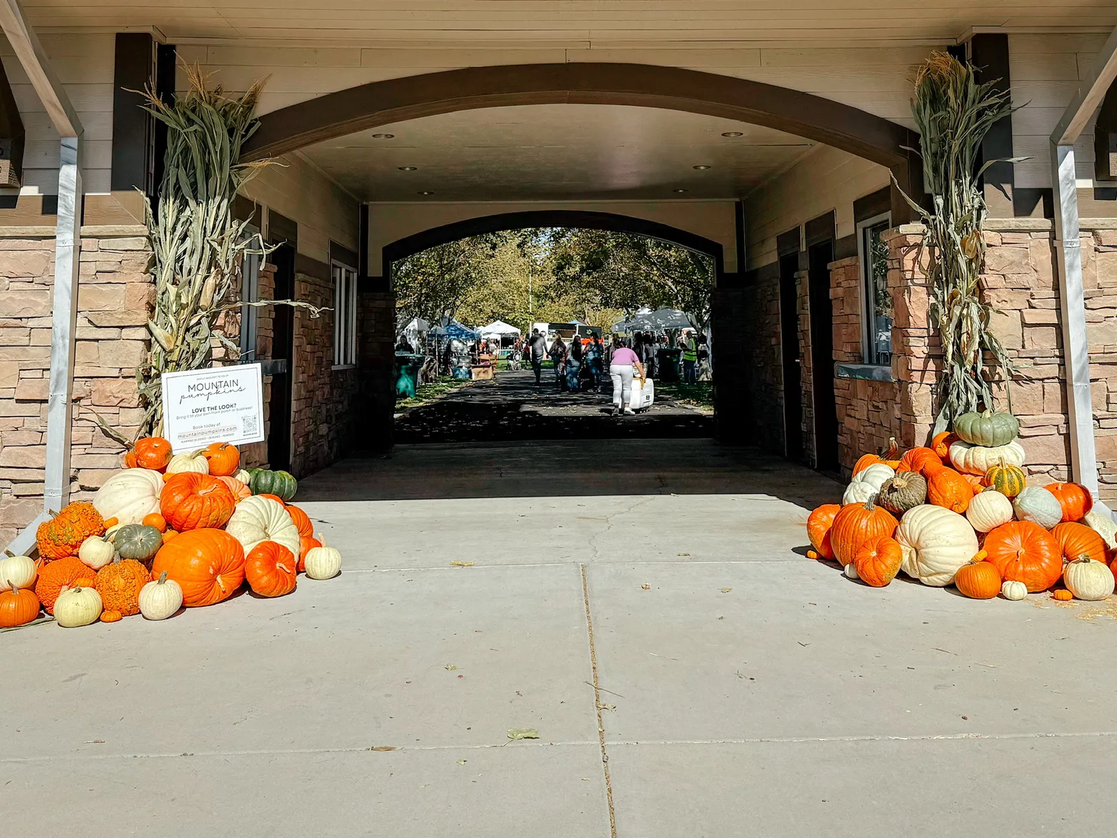 Pavilion archway framed by matching pumpkin mounds and corn stalk bundles